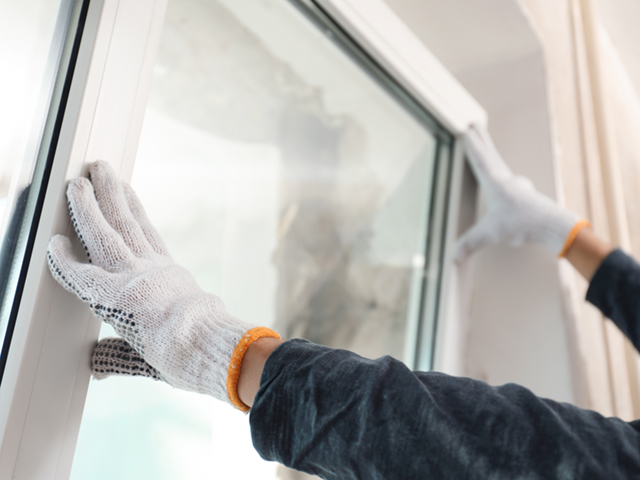 Worker installing plastic window indoors, closeup view